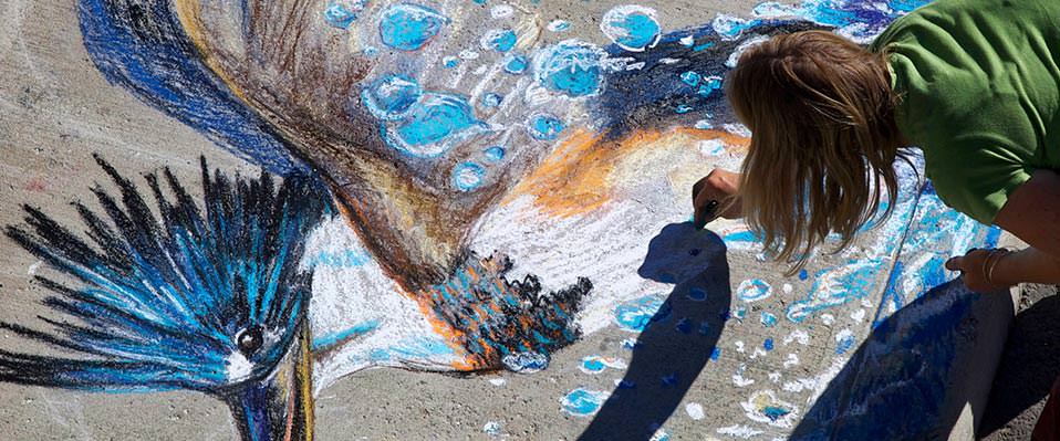 Künstlerin malt mit Kreide auf den Boden